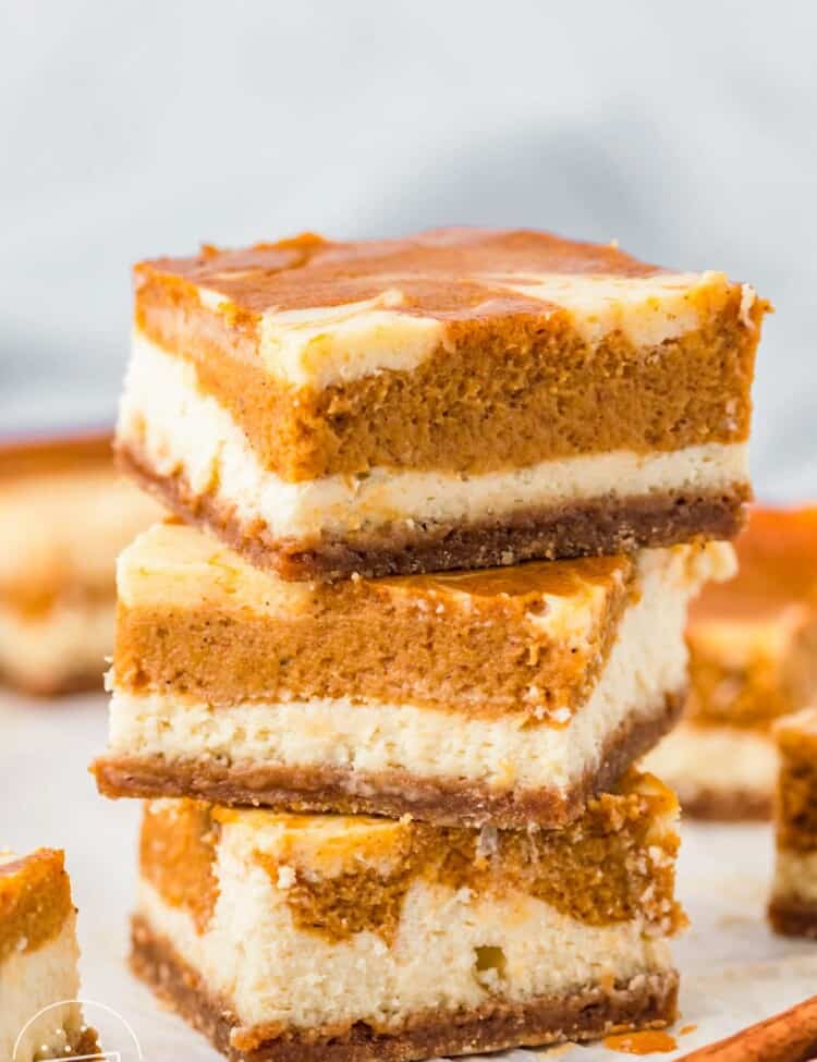 three pumpkin cheesecake bars stacked on top of each other.