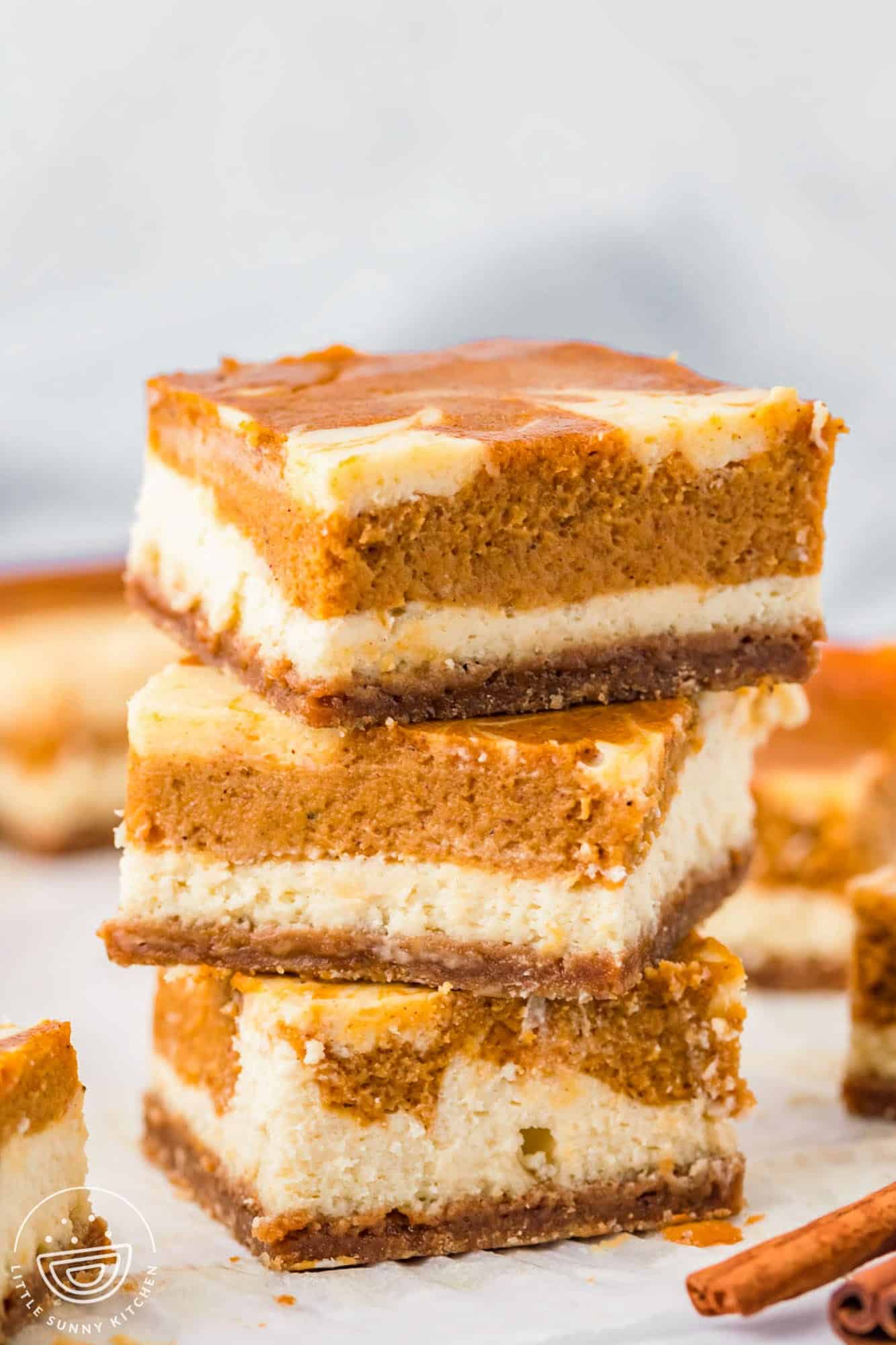 three pumpkin cheesecake bars stacked on top of each other.