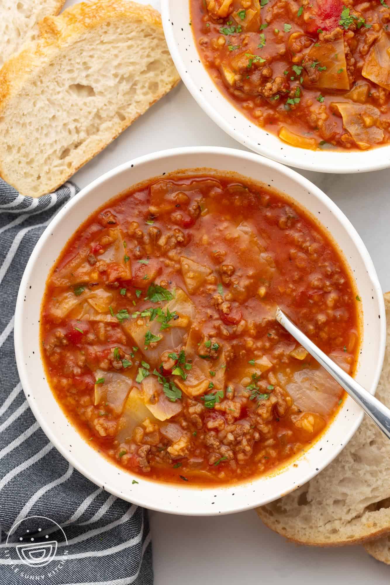 stuffed cabbage soup in serving bowls with fresh bread on the side.