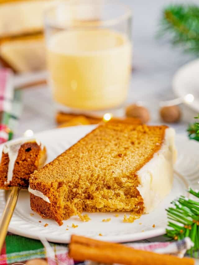 A bite shot of eggnog bread on a white plate with a fork on the side