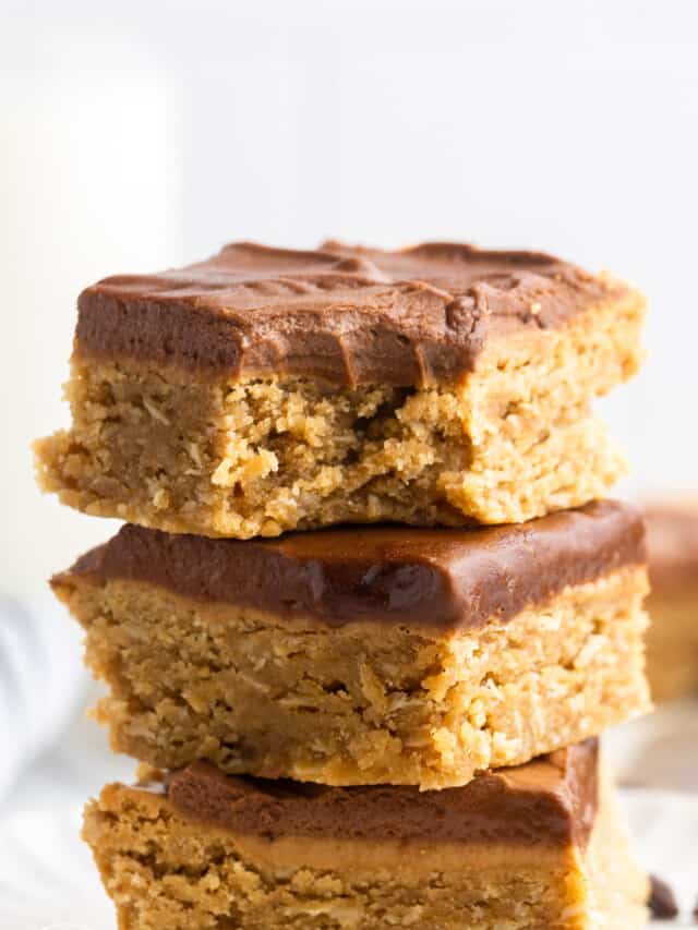 three soft peanut butter bars with frosting, stacked on top of each other.