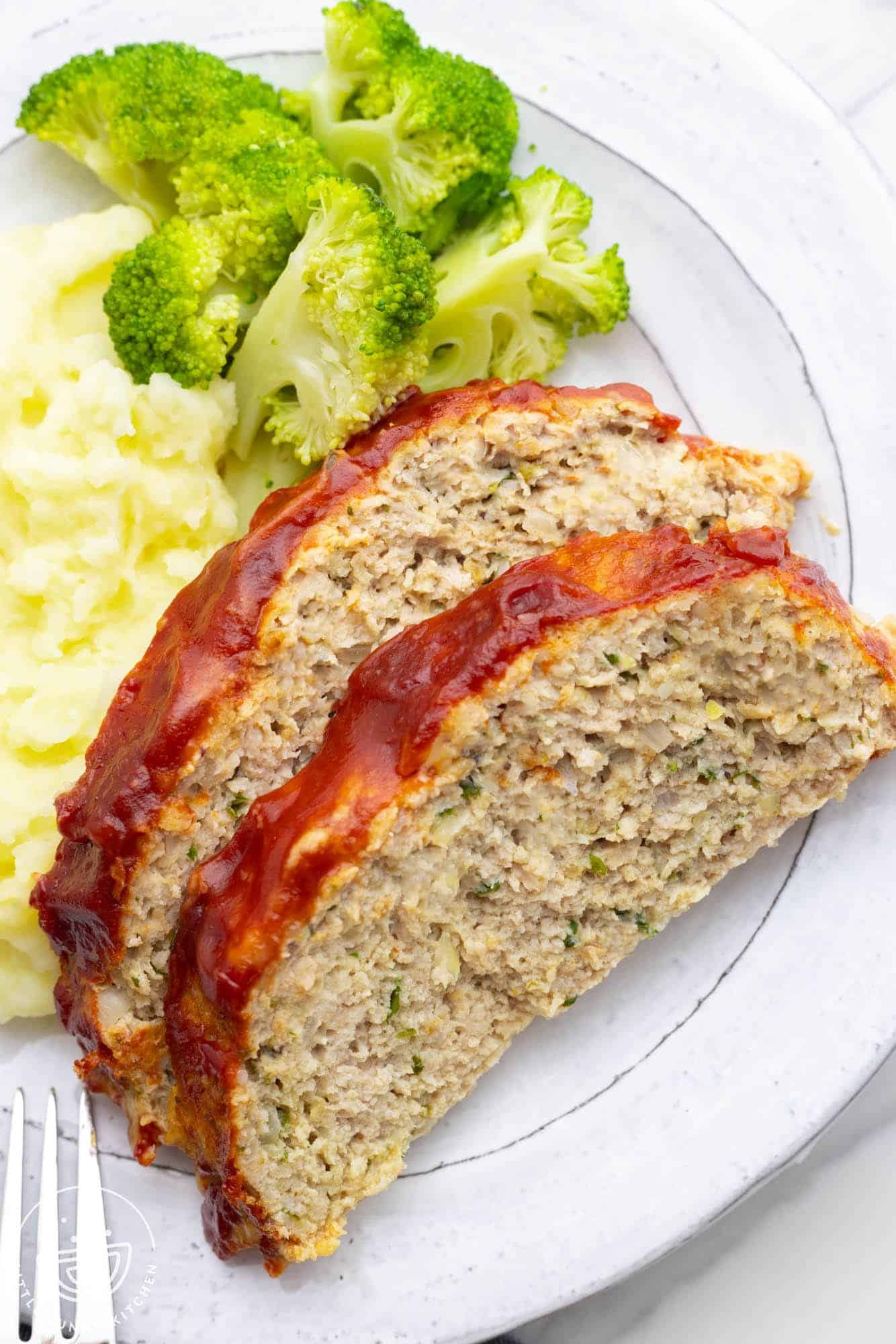 a dinner plate of two slices of chicken meatloaf with potatoes and broccoli.