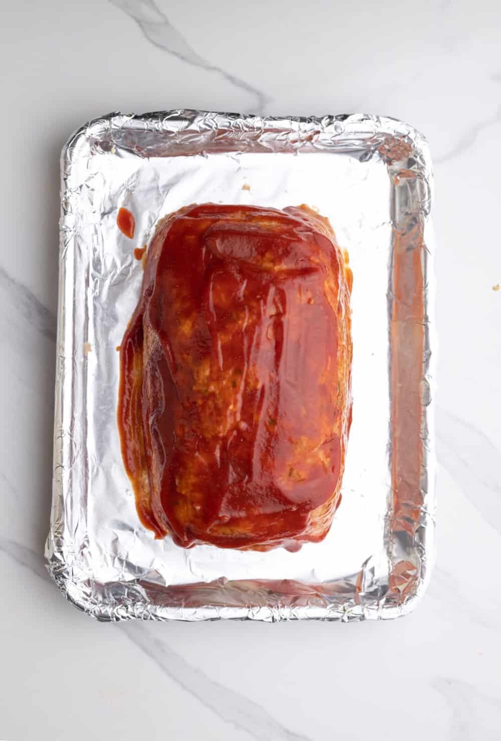 chicken meatloaf covered in a glaze, on a pan.