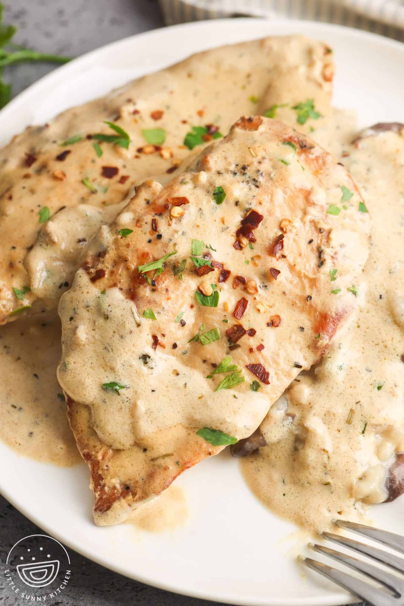 a plate of chicken cutlets in a cream cheese sauce with mushrooms. 