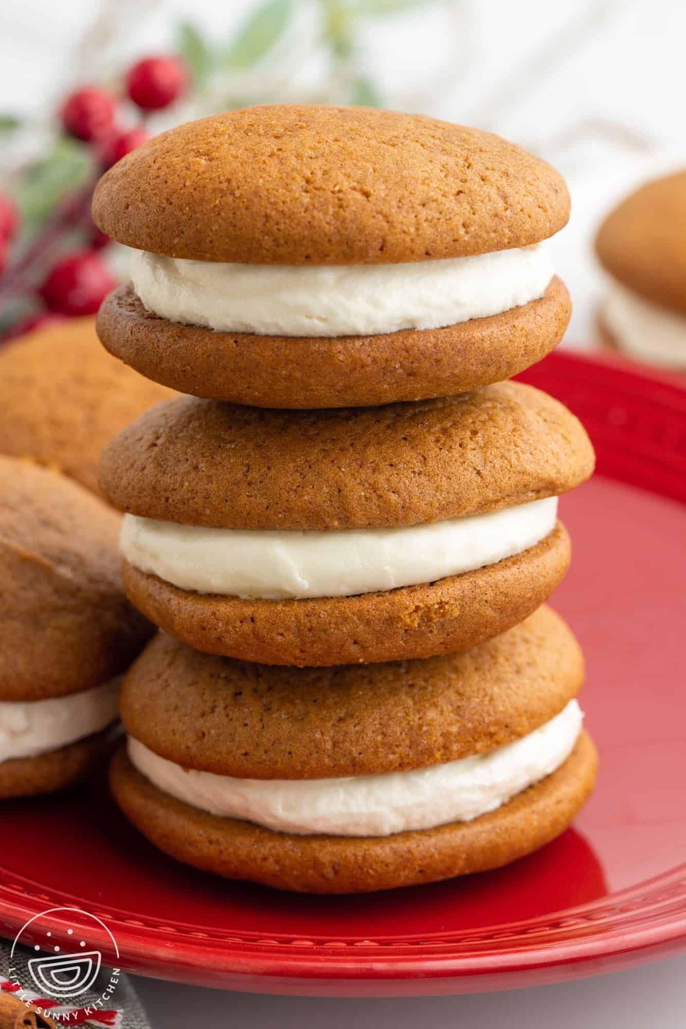 three gingerbread whoopie pies stacked on a plate.