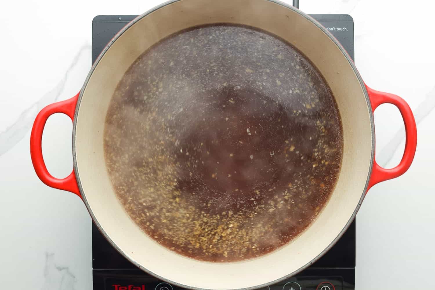 Homemade shuyo ramen broth simmering in a dutch oven