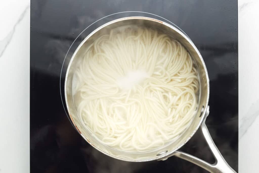 Straight ramen noodles boiling in a pot.