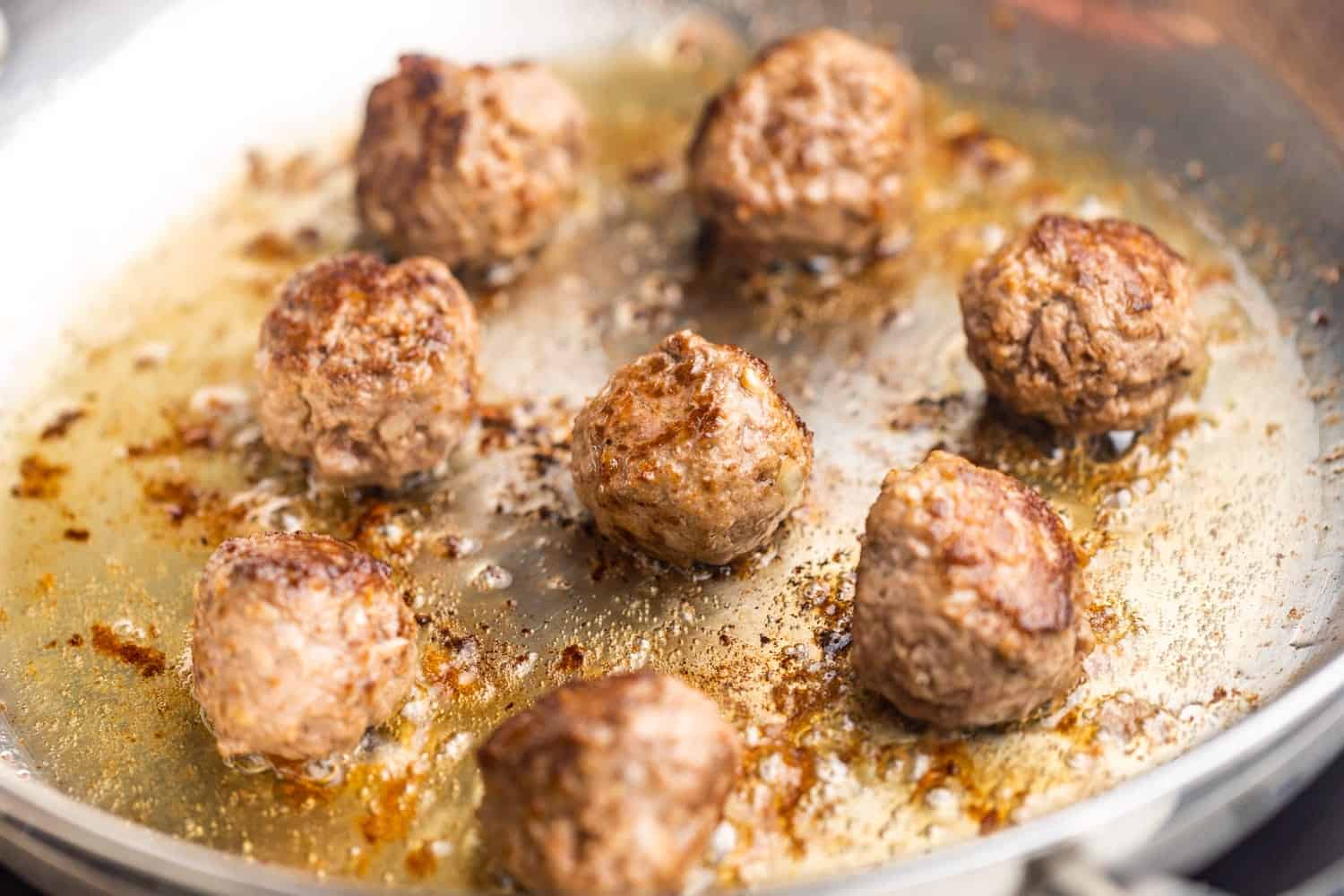 homemade spiced ikea meatballs browned in a stainless steel skillet