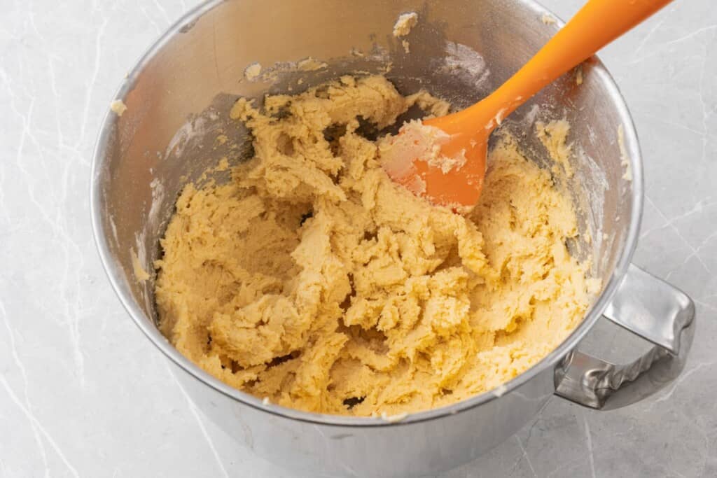 The simple dough for italian butter cookies in a stand mixer bowl with a spoon.