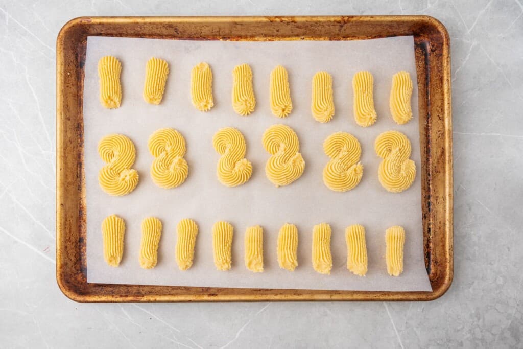 A tray of piped italian cookies in lines and s shapes