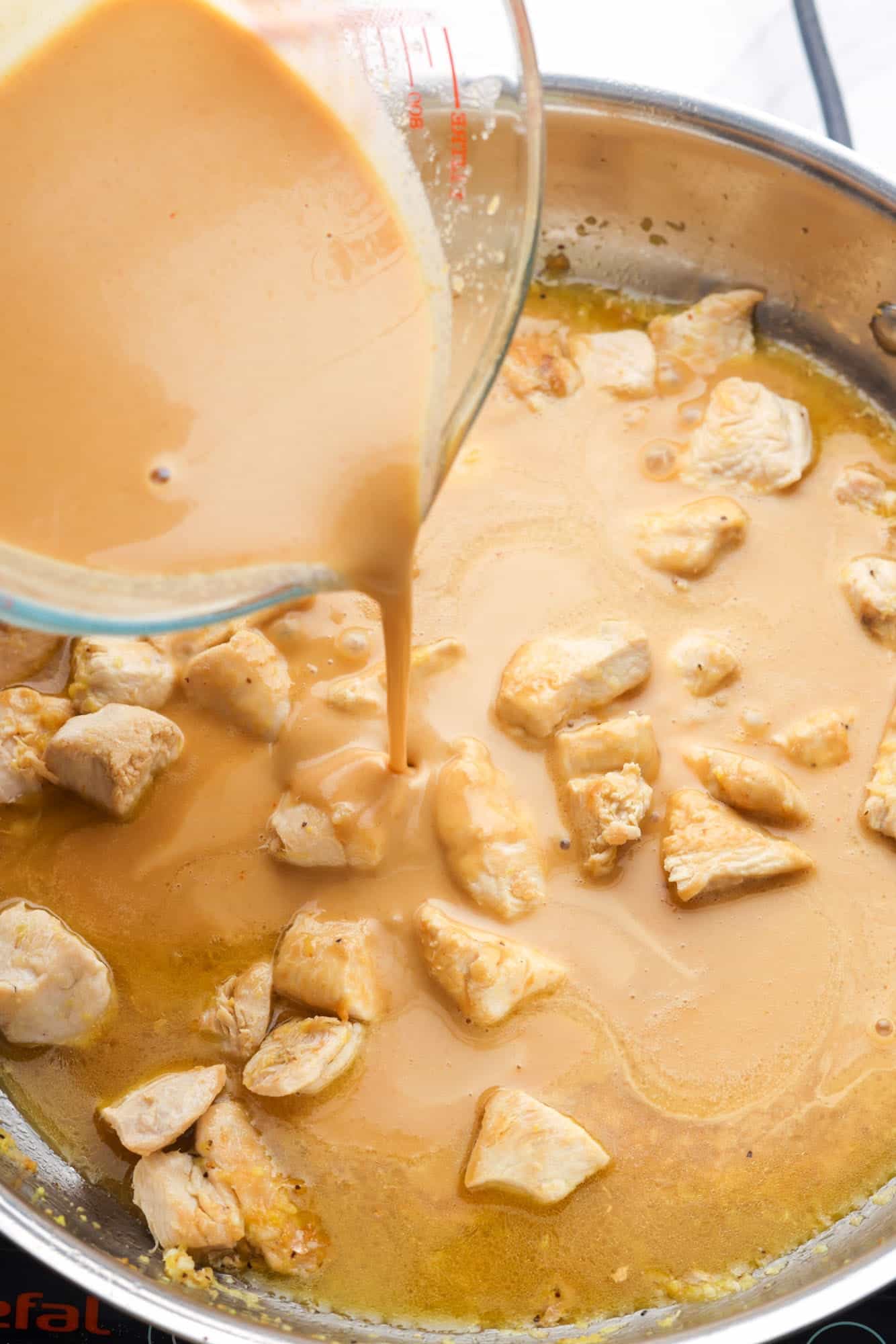 peanut sauce added to chicken in a pan.