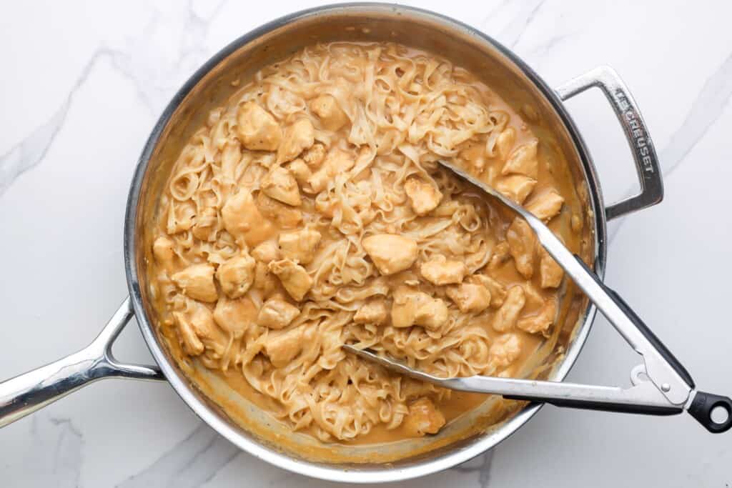 a skillet of creamy peanut noodles with chicken.