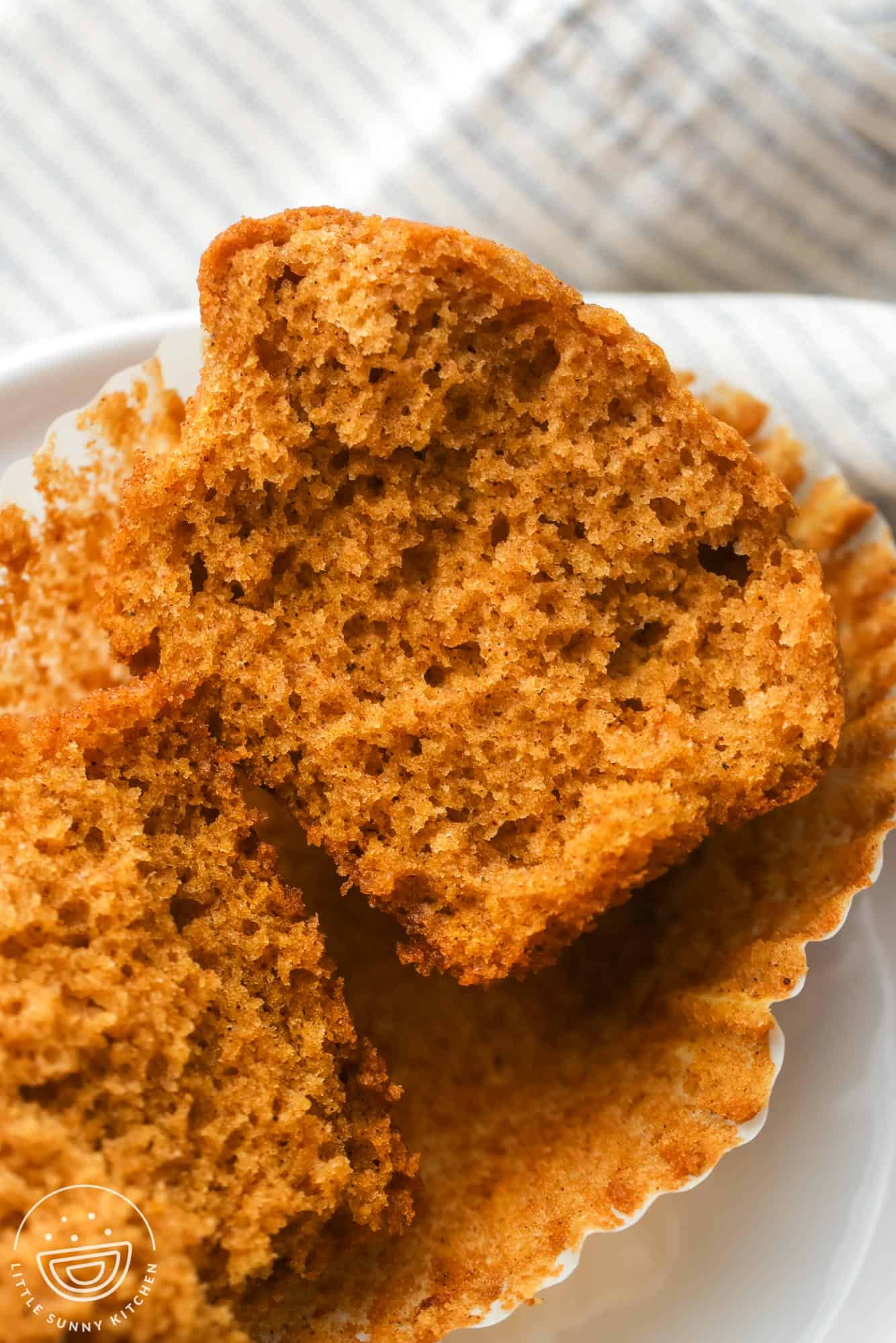 a pumpkin banana muffin split in half to show the moist airy inside.
