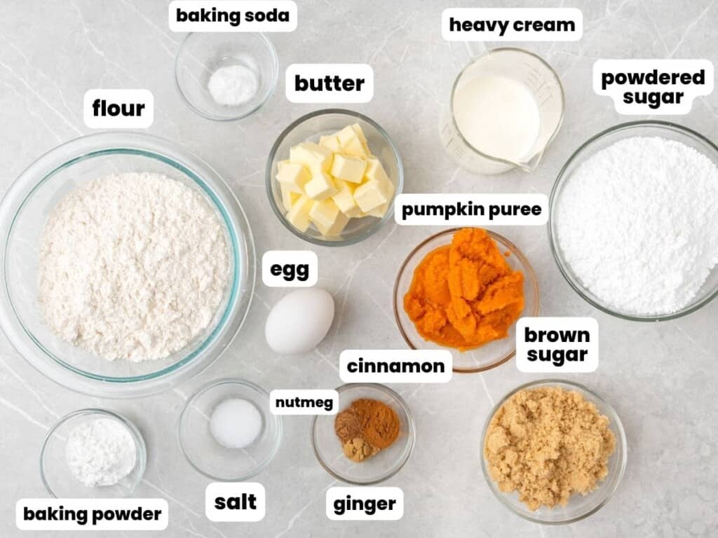 The ingredients needed to make pumpkin scones from scratch, all measured into bowls and arranged on a counter.