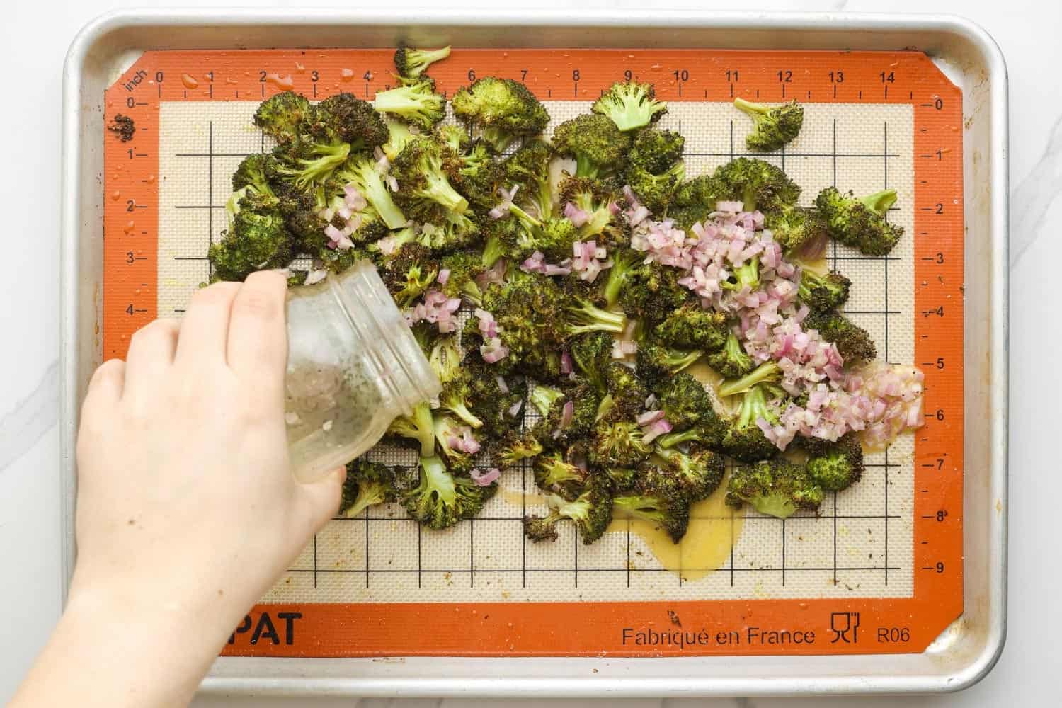 Dressing the roasted broccoli with a shallot vinaigrette