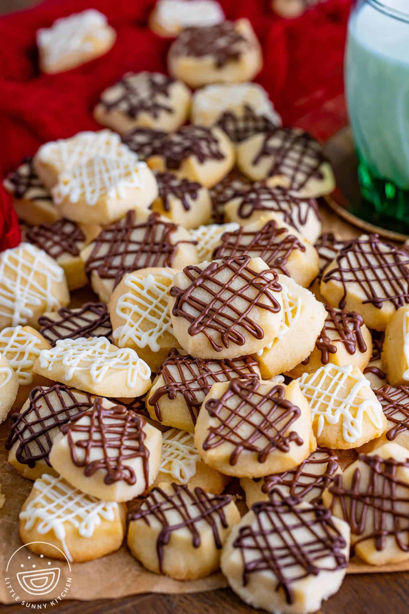 a pile of chocolate drizzled shortbread bites on a red tablecloth.