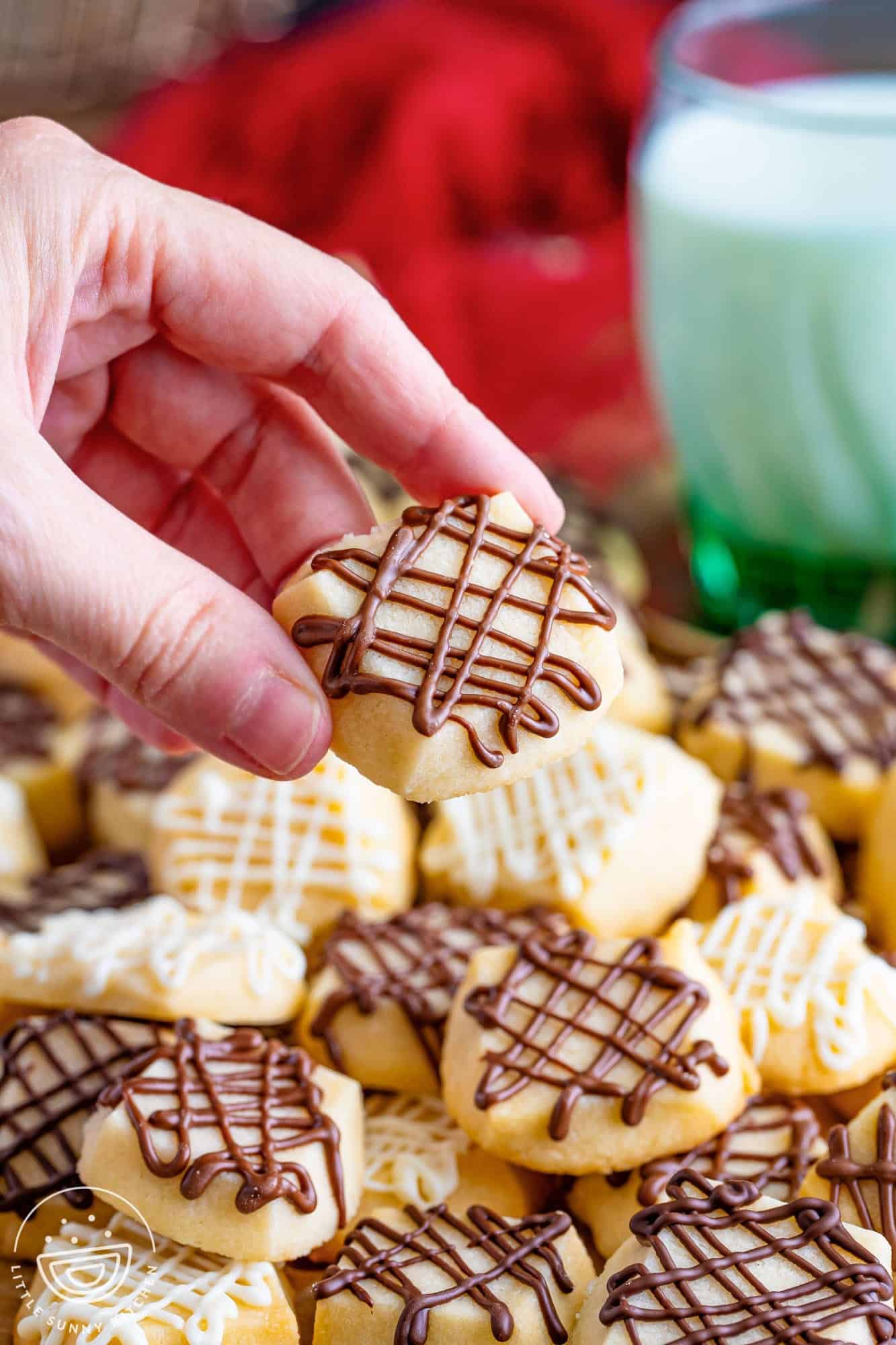 a hand holding a shortbread cookie with chocolate drizzled on top.