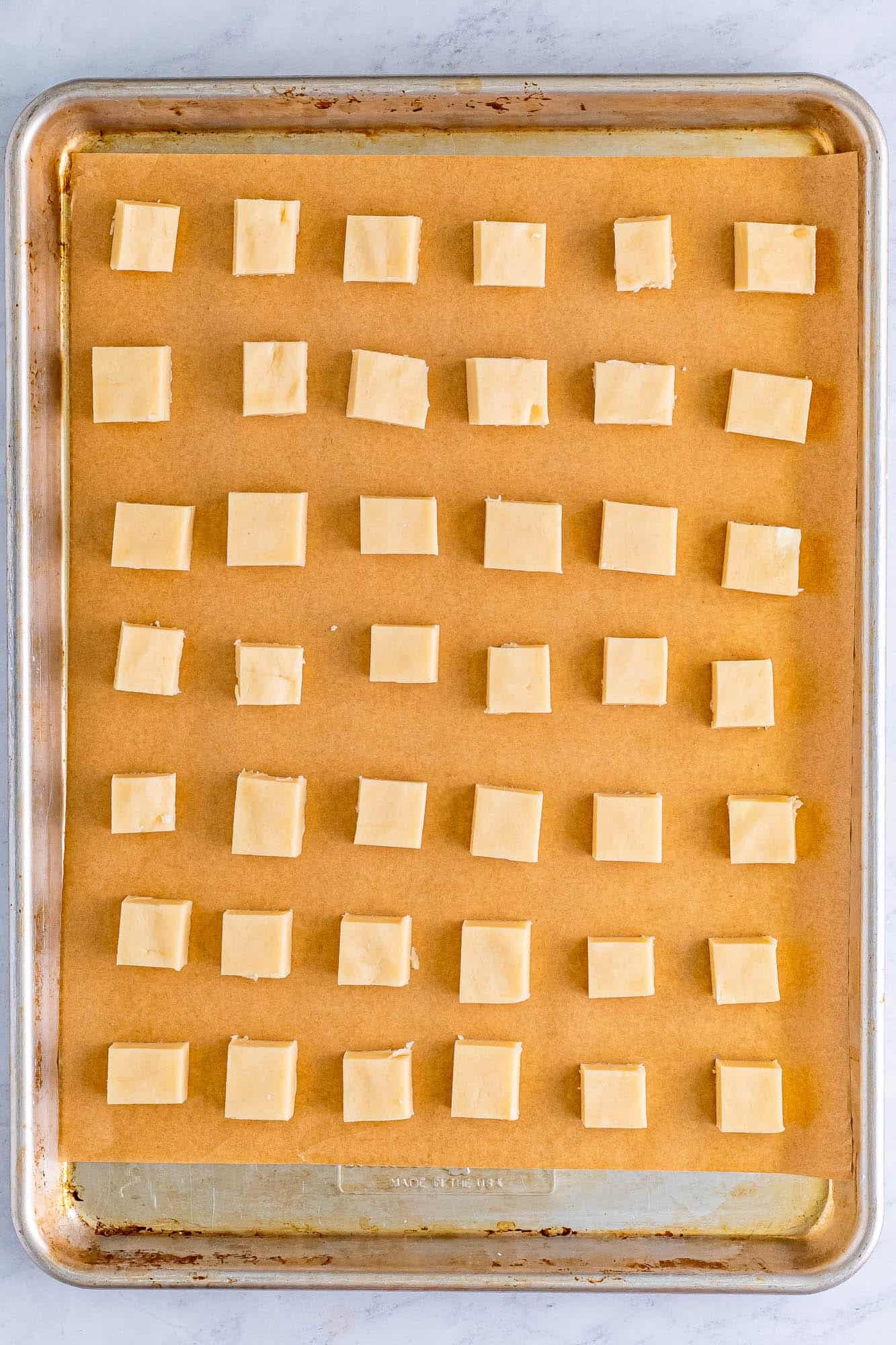 small squares of shortbread dough on a baking sheet lined with parchment.