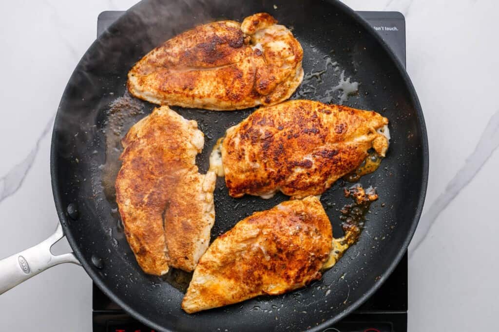 taco seasoned chicken breasts cooking in a skillet.