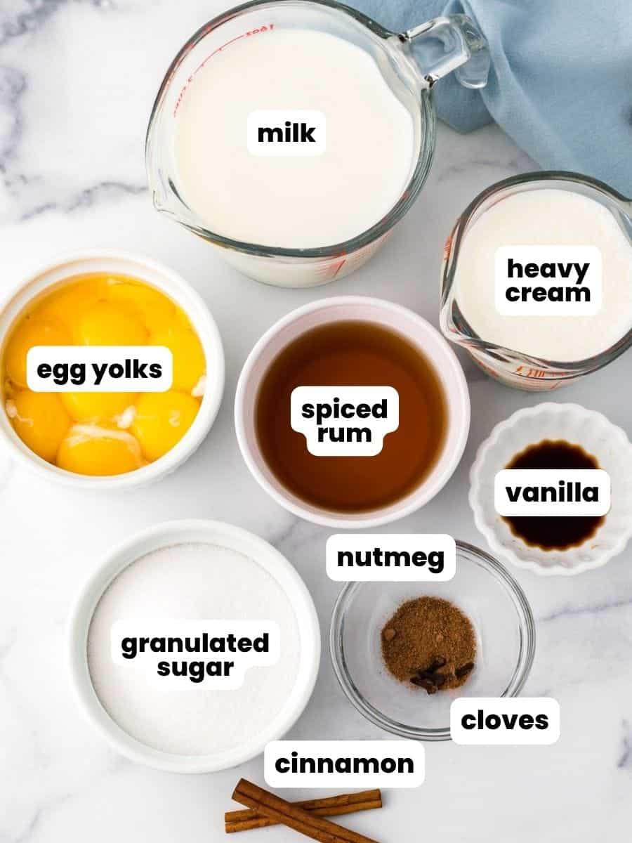 The ingredients needed to make homemade spiked eggnog with egg yolks, spiced rum, and cream.