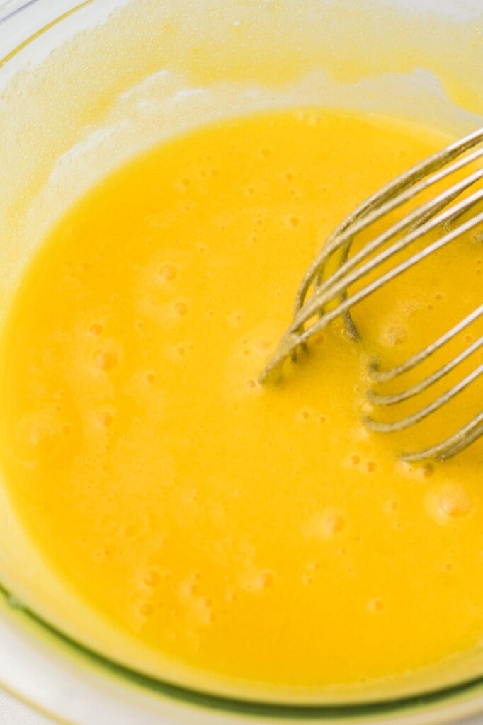 egg yolks whisked in a glass bowl.