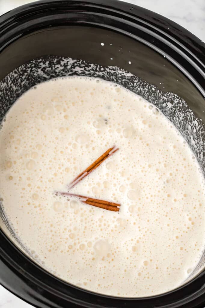 eggnog bubbling in a crock pot with cinnamon sticks.