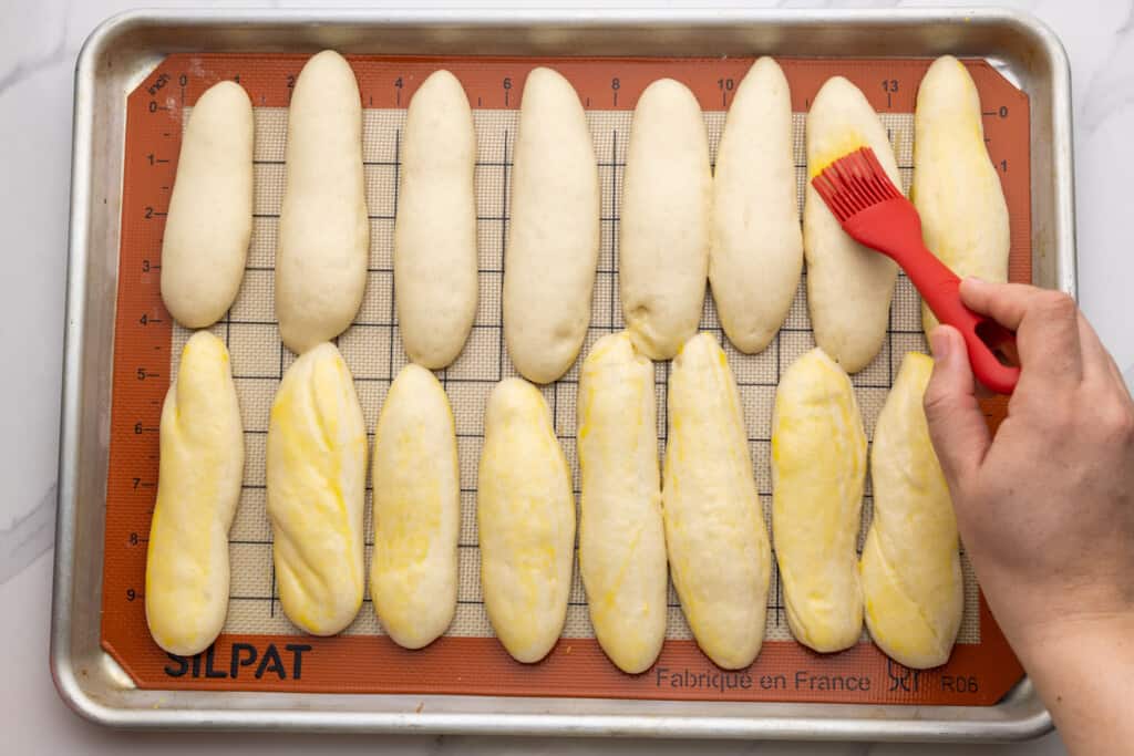 Egg wash being applied on breadstick dough before baking