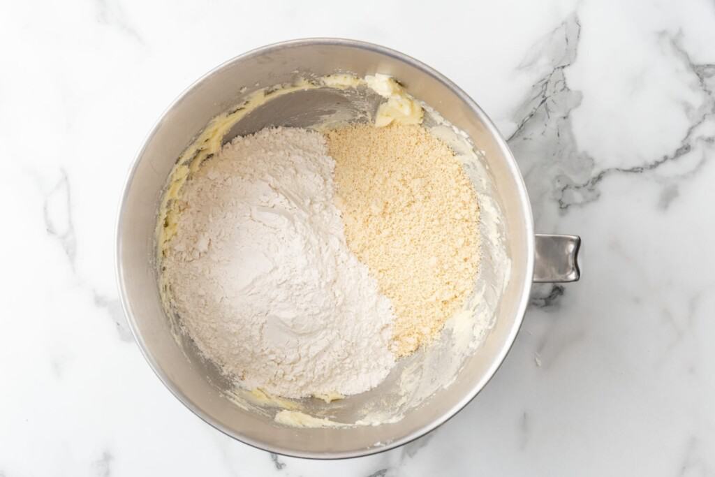 all purpose flour and almond flour added to a mixing bowl that is sitting on a marble counter.