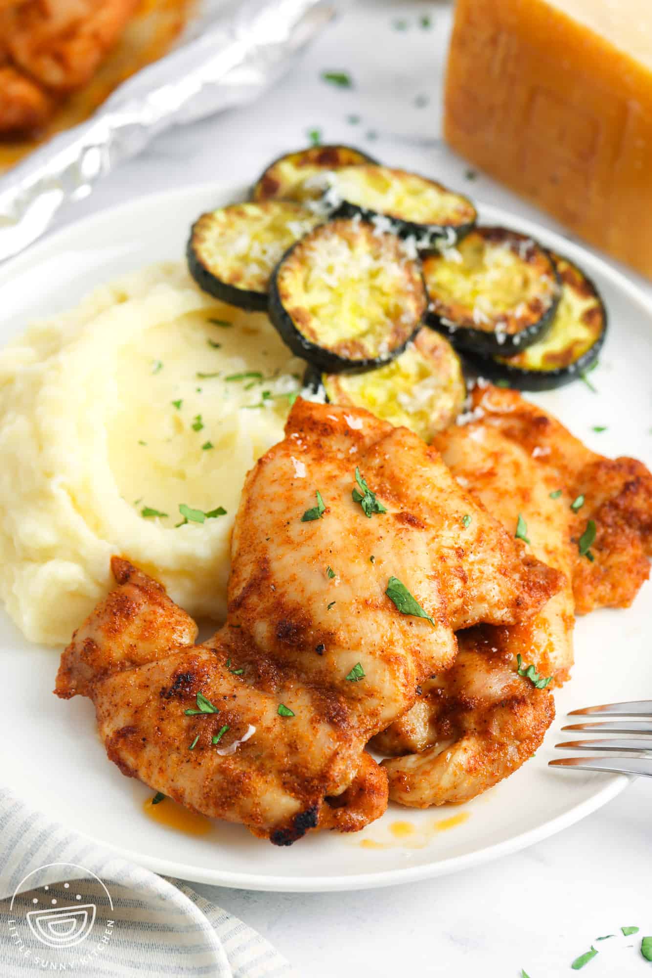 a dinner plate of baked boneless chicken thighs, zucchini, and mashed potatoes