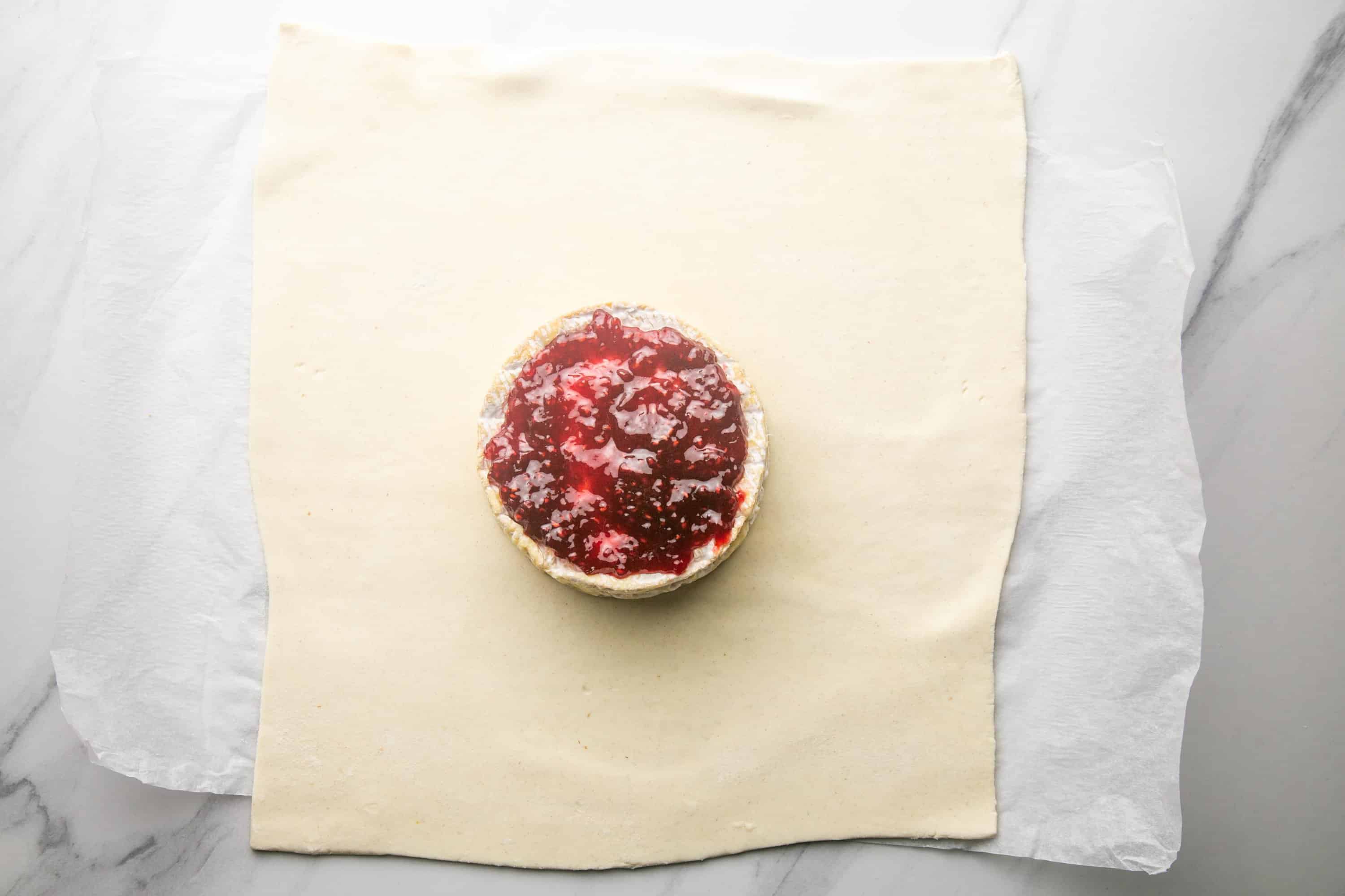 Overhead shot of brie topped with jam, placed on a sheet of puff pastry