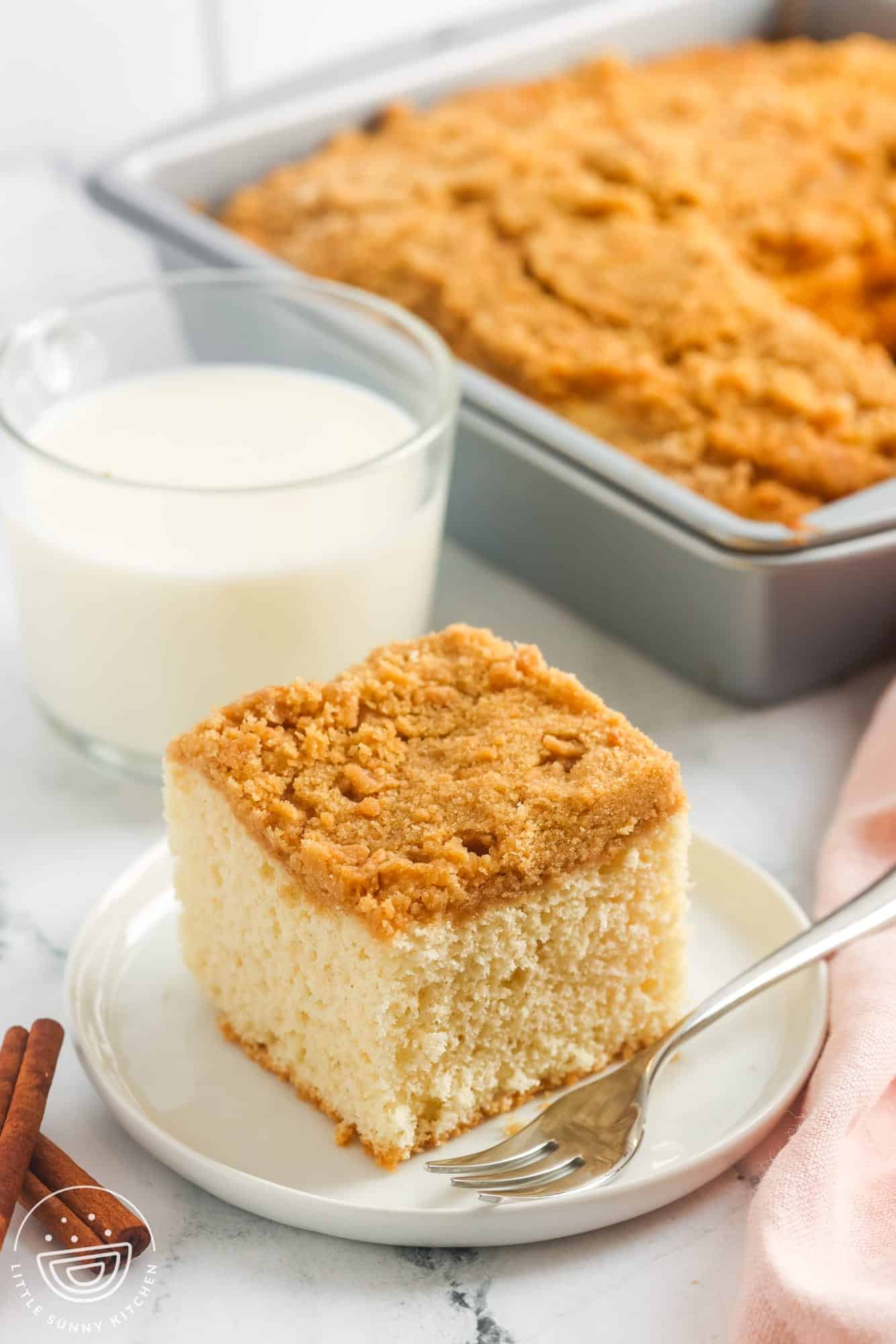 a square of fluffy bisquick coffee cake on a plate next to a glass of milk.