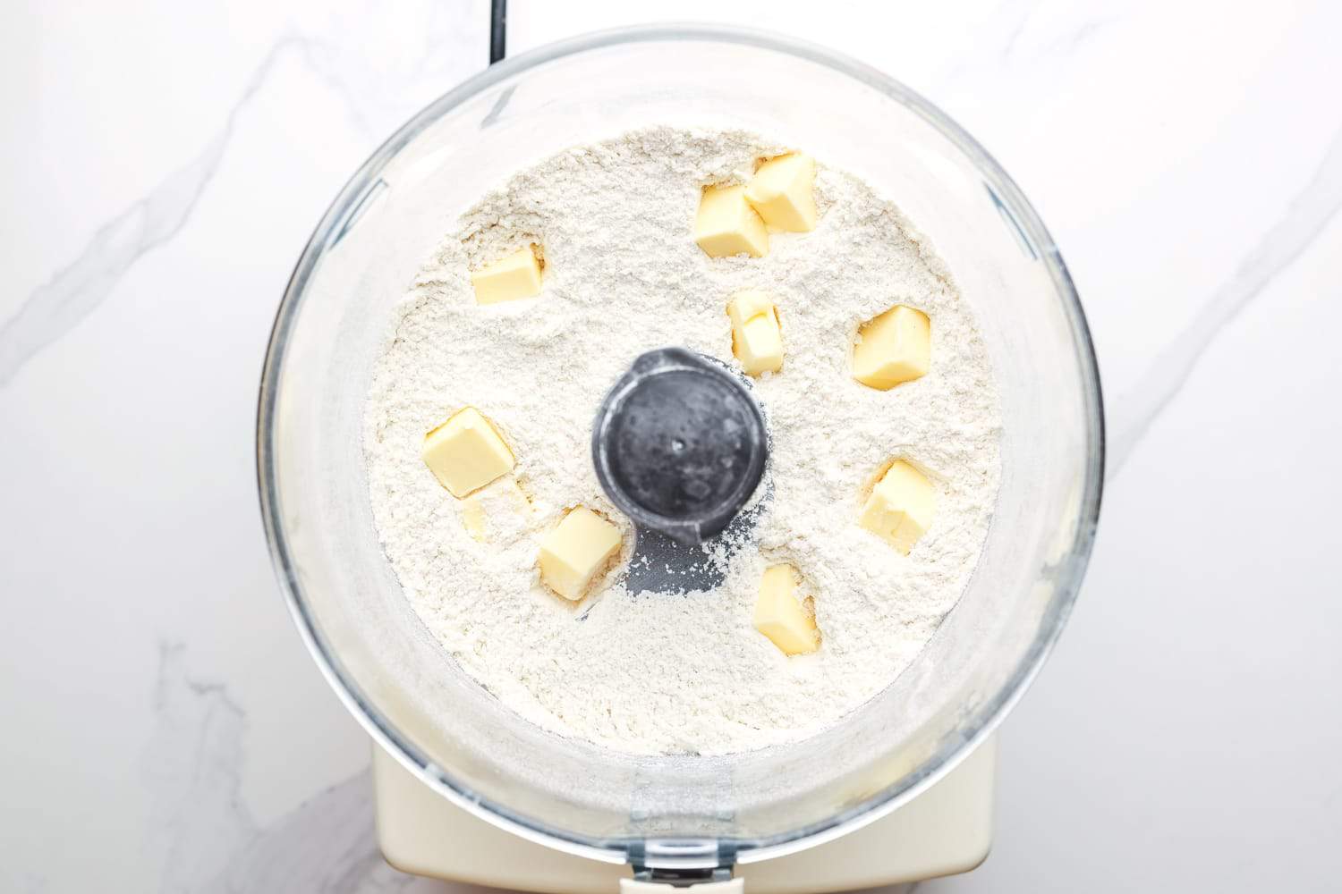flour and cubes of butter in the bowl of a food processor. 