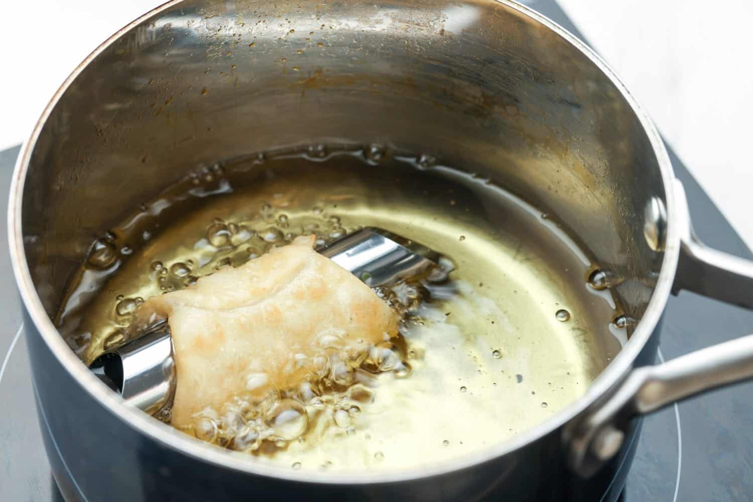 one cannoli frying in hot oil. 