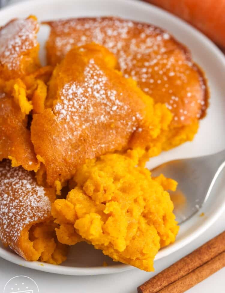 Carrot Souffle served on a white plate, with a fork on the side and a cinnamon stick