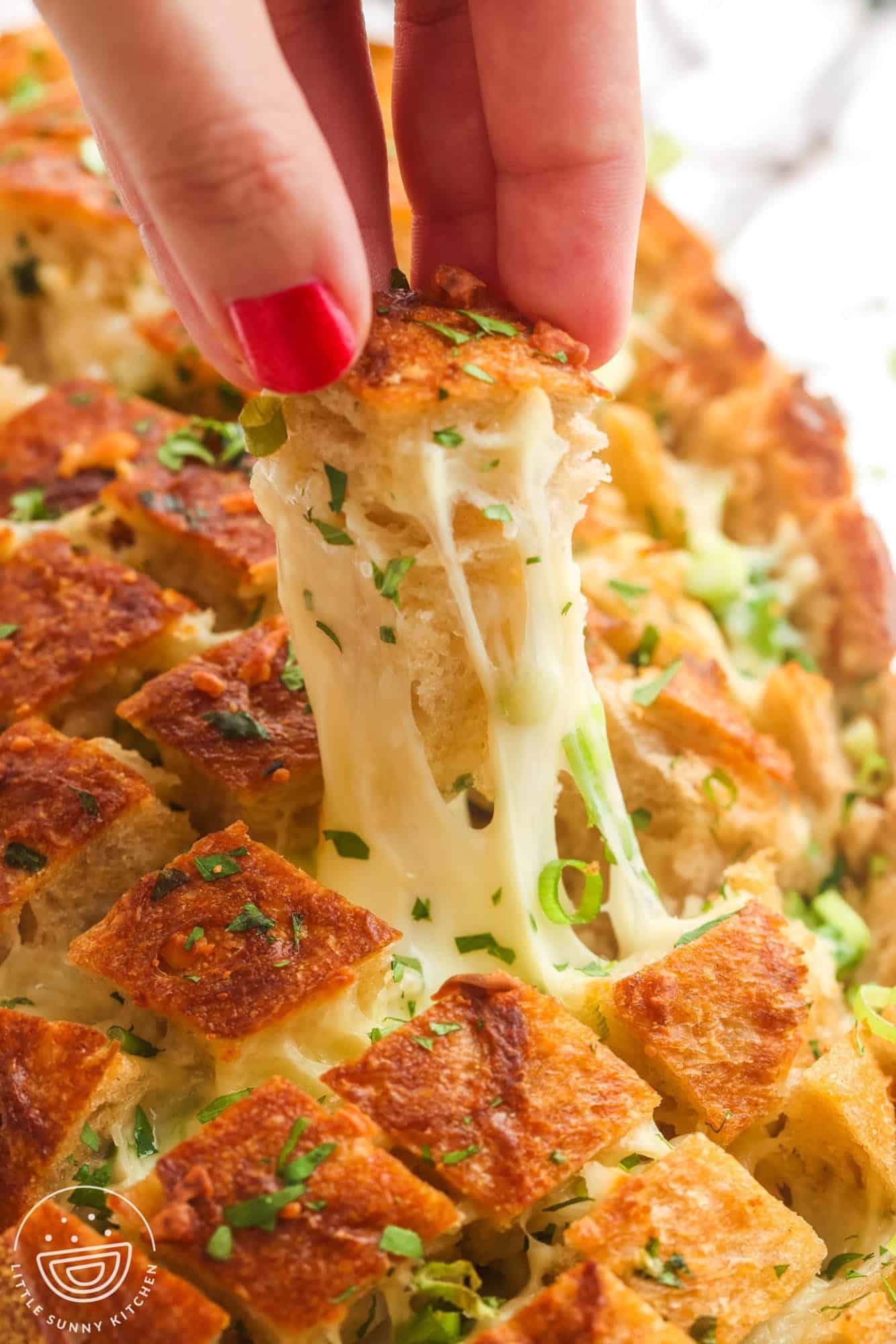 cheesy garlic pull apart bread. A hand is picking up a piece, showing the cheese pull.