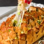 a hand picking up a piece of garlic pull apart bread