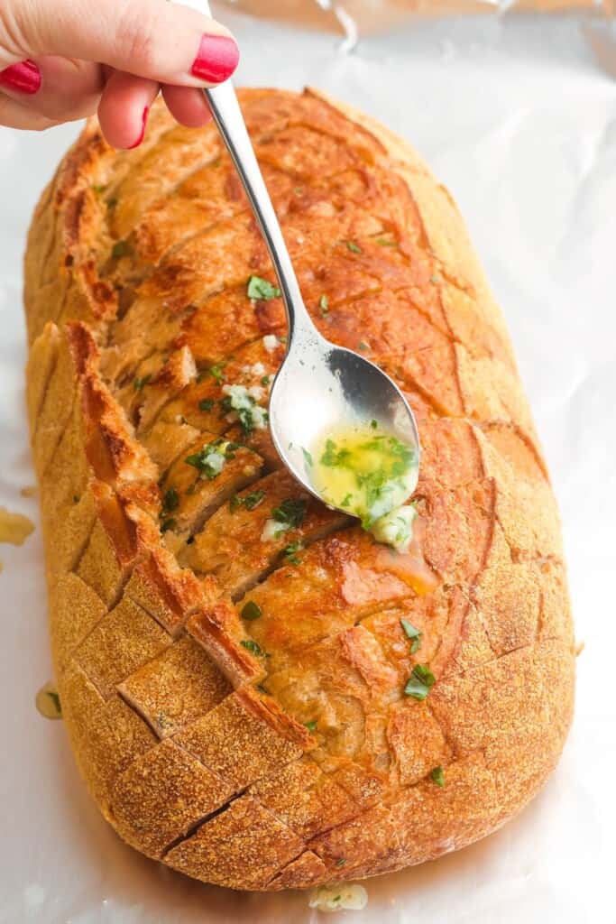 spooning melted garlic butter into the spaces of pull apart bread
