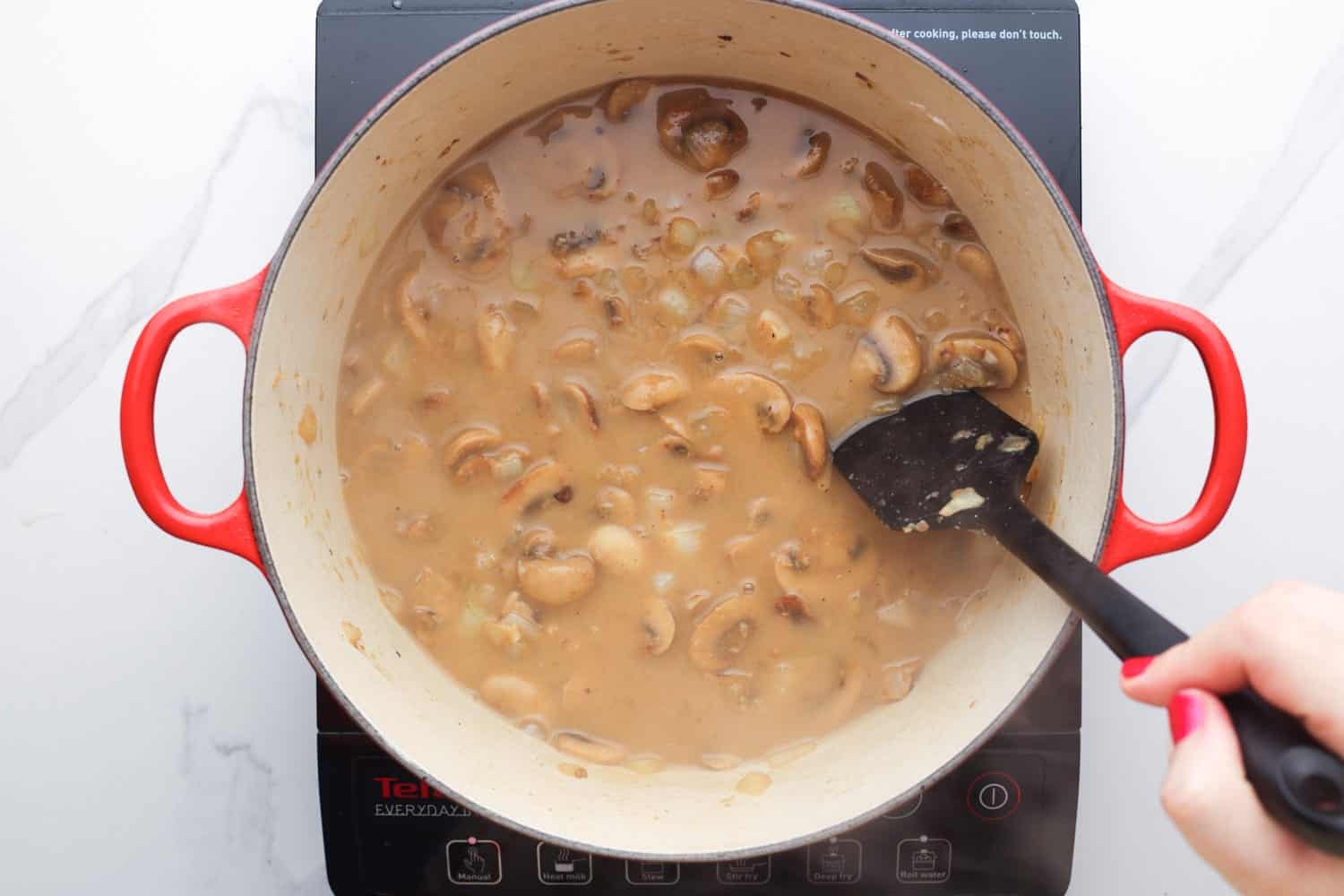 mushroom sauce stirred in a pat with a black spatula