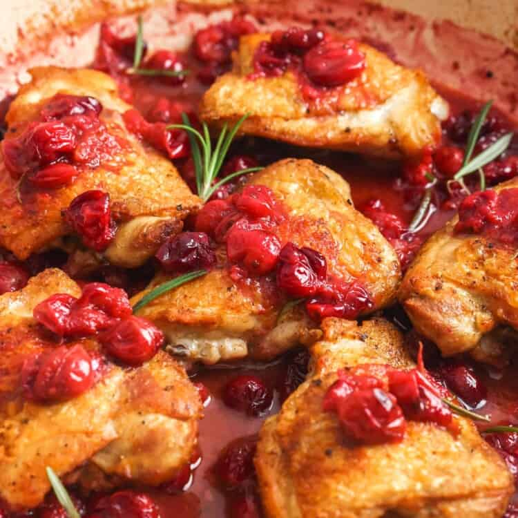 cranberry topped chicken thighs in a pan.