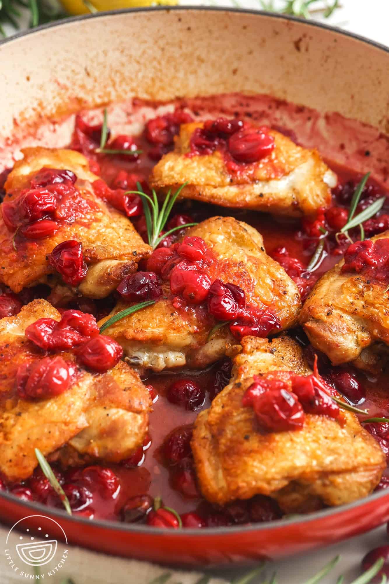 cranberry topped chicken thighs in a pan.