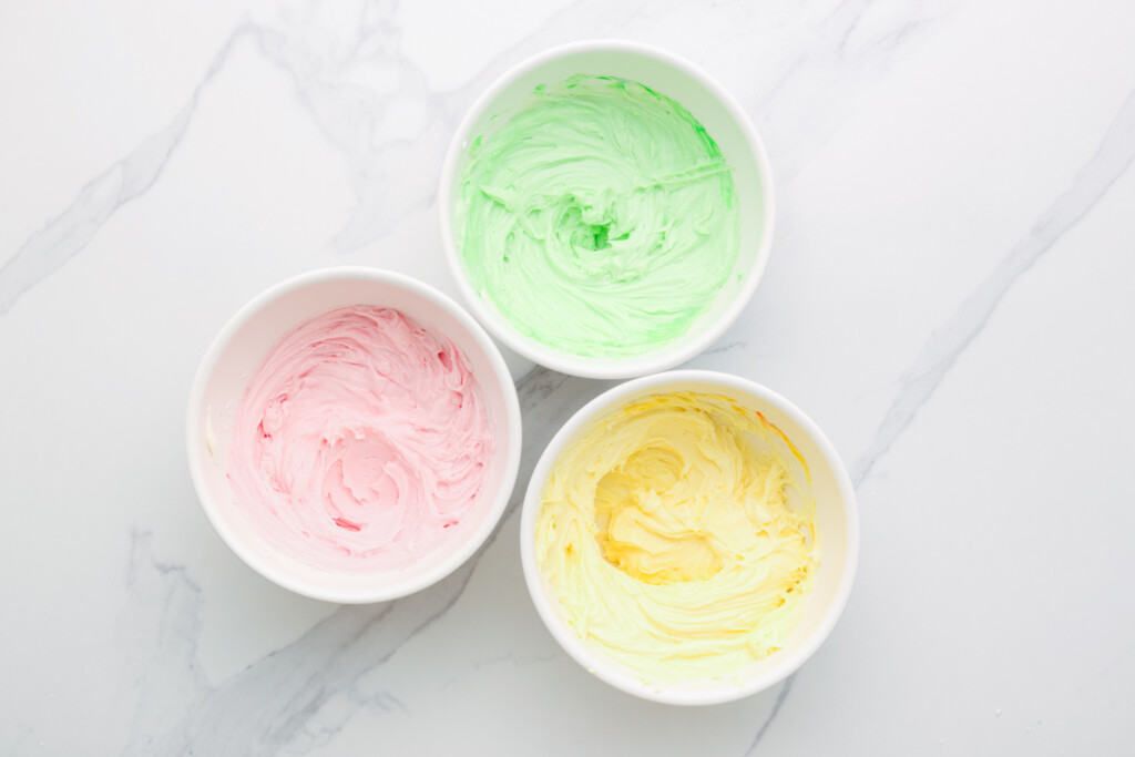 the batter for mints in separate bowls, colored pink, green, and yellow.