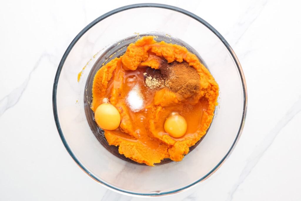 pumpkin puree, eggs, and spices in a glass mixing bowl