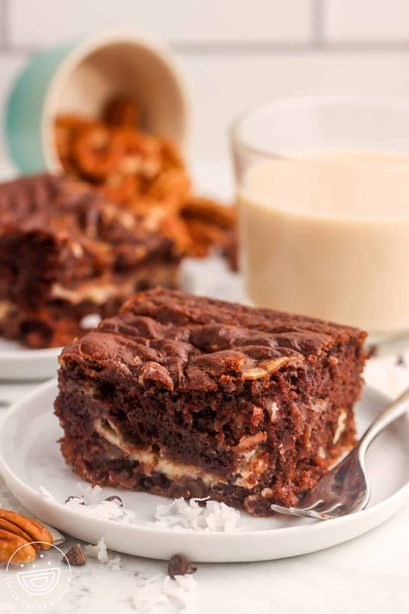 a square piece of loaded chocolate cake in front of a glass of milk.