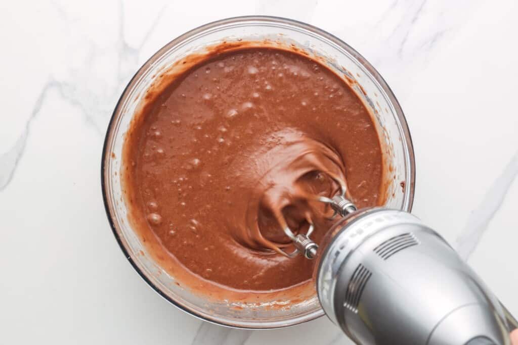 a hand mixer mixing chocolate cake mix