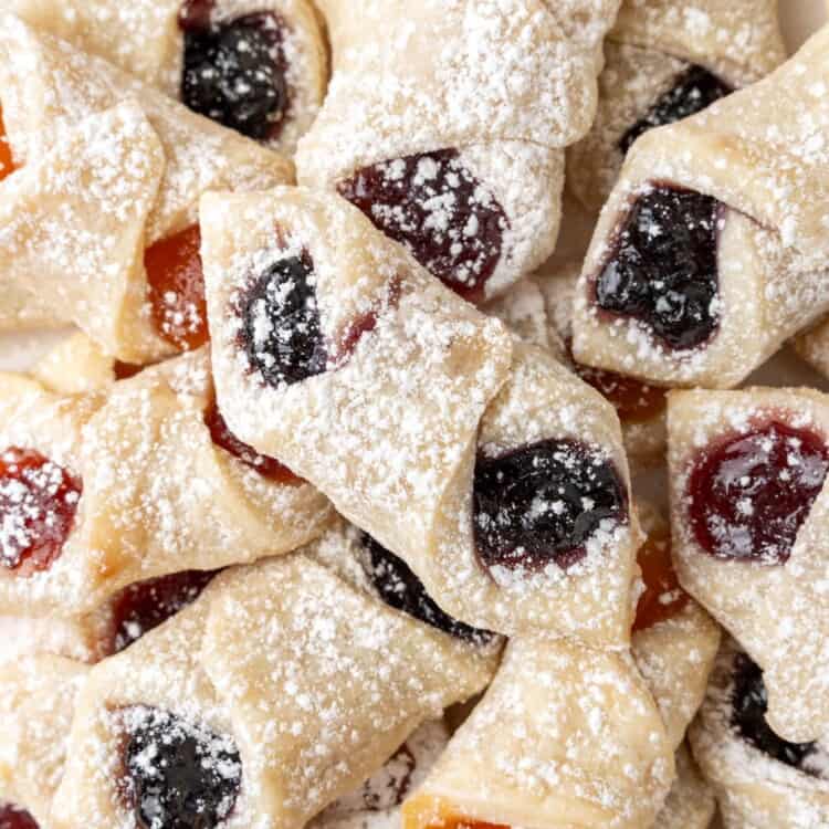a pile of kolaczki with fruit filling, dusted with powdered sugar.