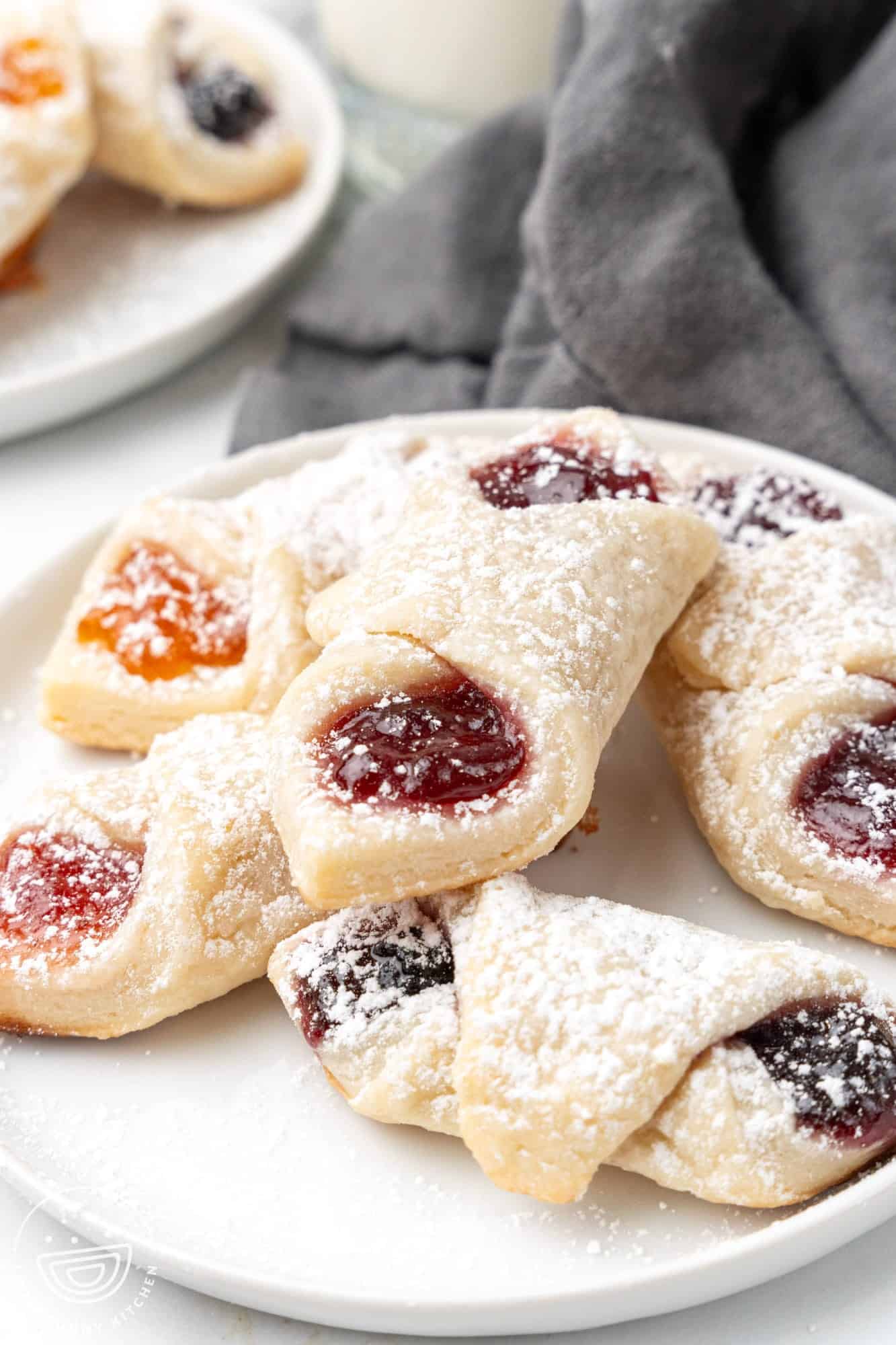 a small plate holding six fruit filled polish cookies that are dusted with powdered sugar.