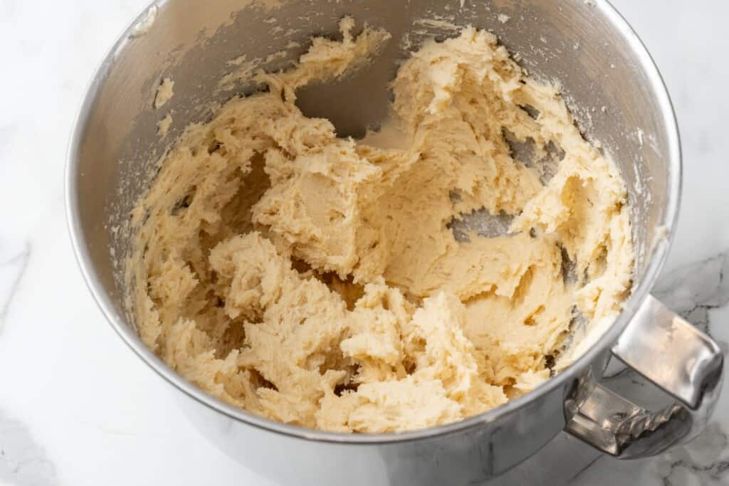 kolaczki cookie dough mixed in a silver stand mixer bowl.