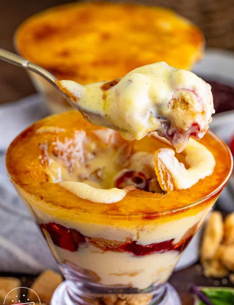 Taking a spoonful of creamy creme brulee top of the mini trifle with a spoon