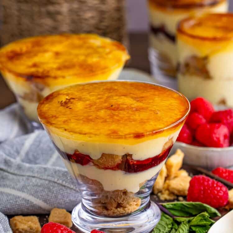 Mini creme brulee trifles in dessert cups, with fresh raspberries on the sides.