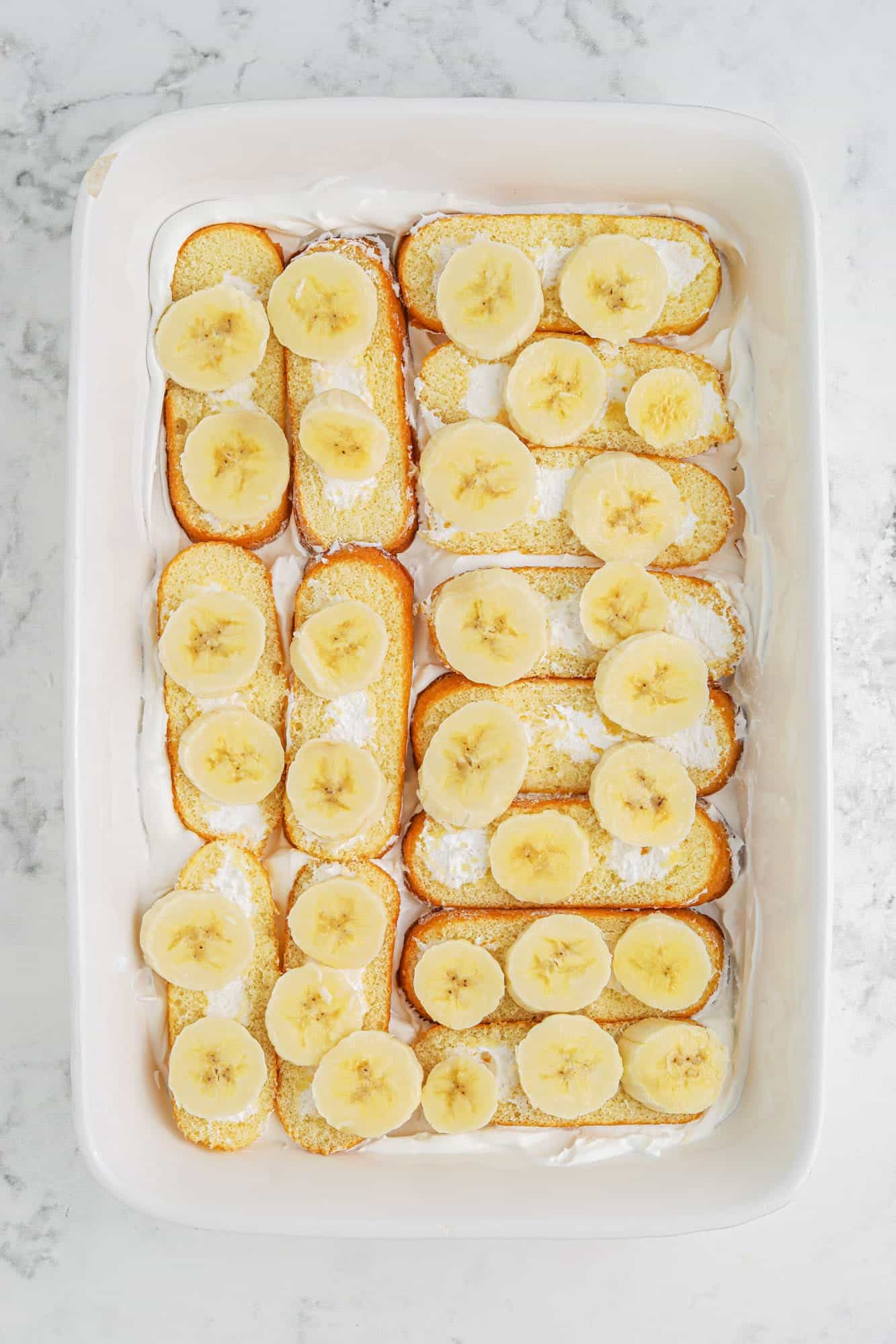 Twinkies laid out in a 9x13 baking dish with sliced bananas on top
